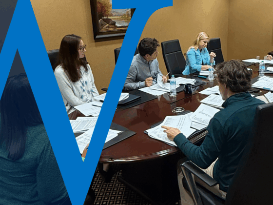interns and young professionals sit around a boardroom table