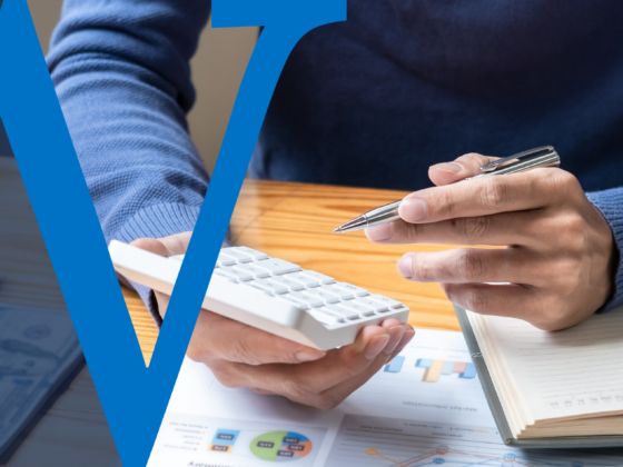 Person using a calculator and pen at a desk with financial documents and a notebook, overlaid with a blue W graphic.