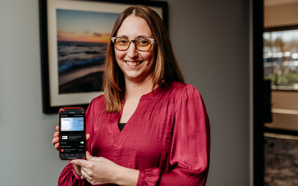 Marissa Hadley holds up a phone that displays an image of mobile banking.