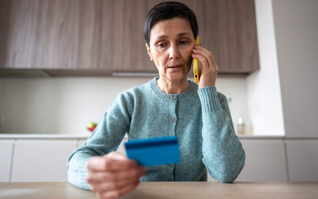 Woman on the phone holding a credit card while reviewing account information.