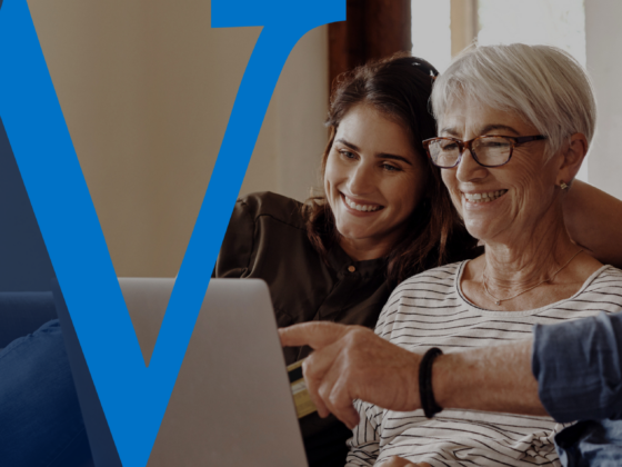 A family sitting together on a couch, smiling while looking at a laptop, with a large blue Waterford “W” overlay on the left side of the image.