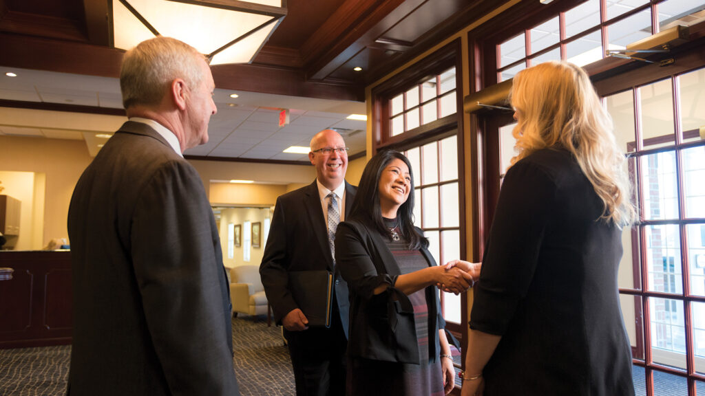 A young professional shakes hands with Waterford bankers, starting a conversation about financial foundations in the next steps of their career.